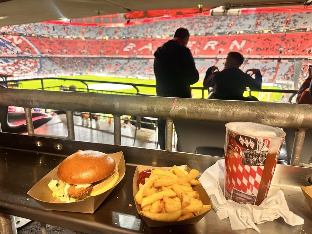 Burger, Pommes und Getränk auf der Tribüne der Allianz Arena