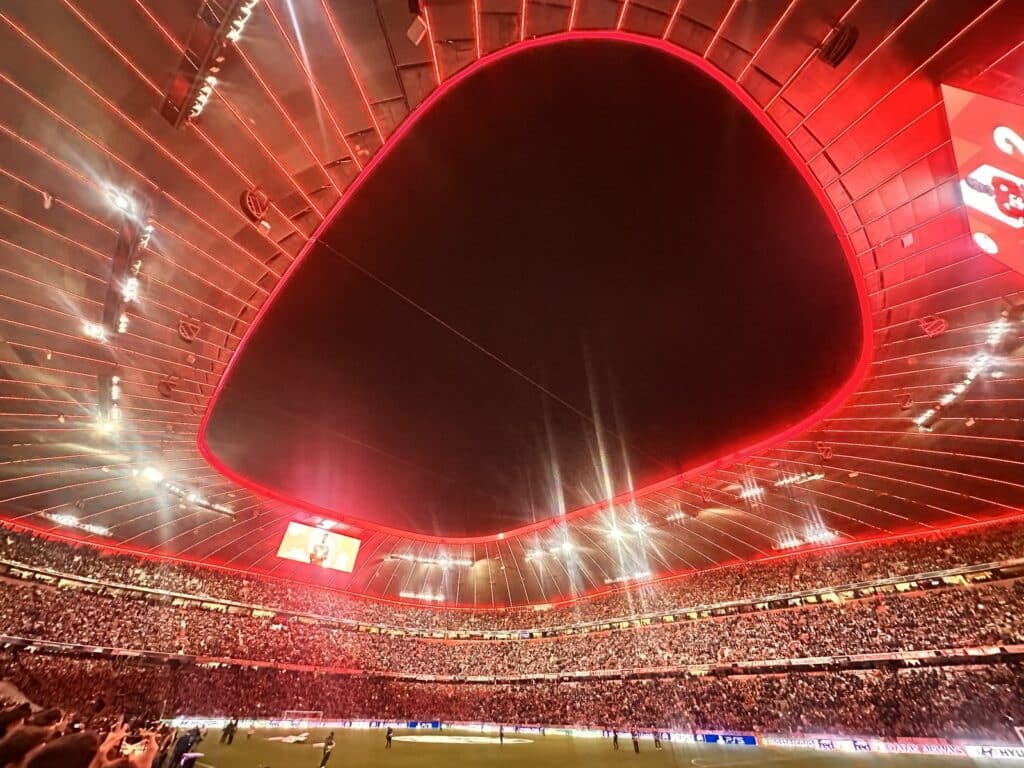 Innenraum der vollen Allianz Arena mit rot beleuchtetem Dach