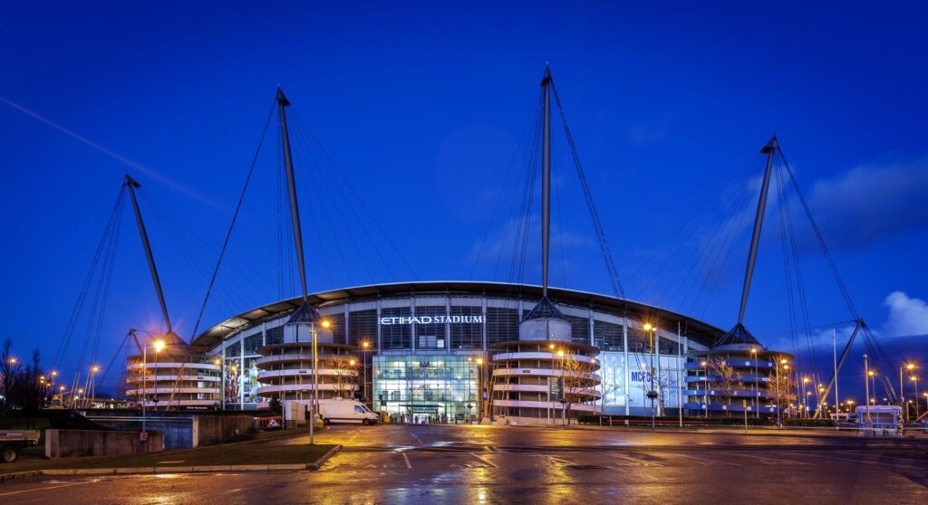 Etihad Stadium in Manchester bei Nacht mit beleuchteten Rampentürmen